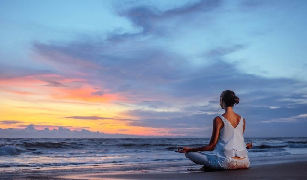 mulher meditando em frente ao mar